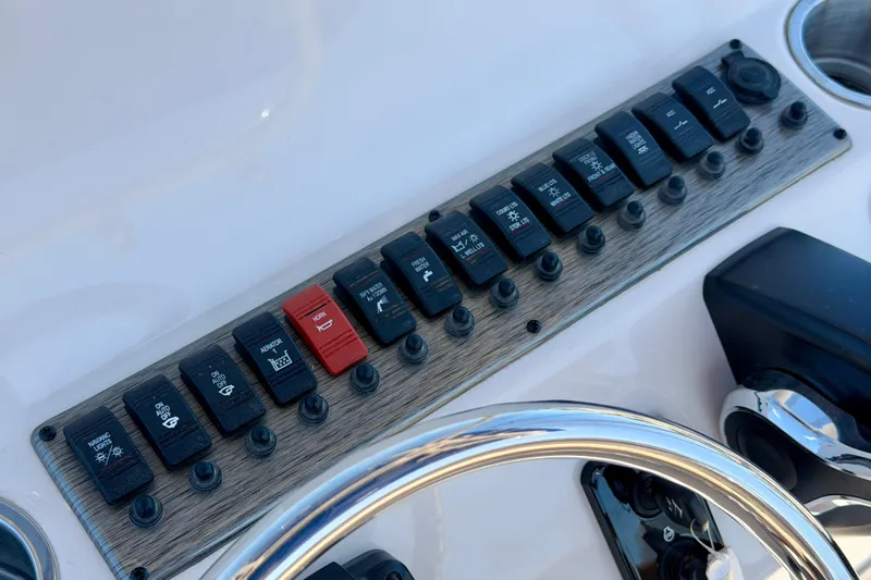 Slide: The Image of Control panel of 2026 Carolina Skiff 24 Ultra Elite boat with labeled switches. - 15