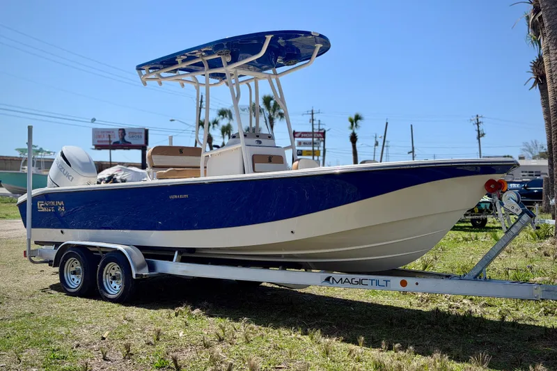 Slide: The Image of 2026 Carolina Skiff 24 Ultra Elite boat on trailer, blue and white design, sunny day. - 28