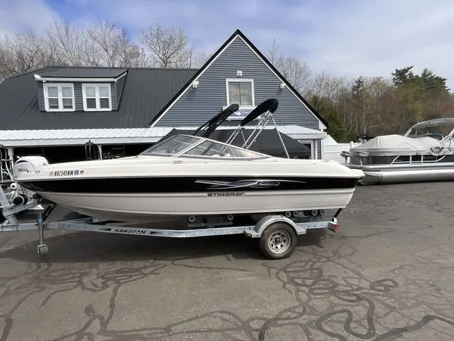The Image of 2013 Stingray 208 LR boat on trailer in front of house. - 1