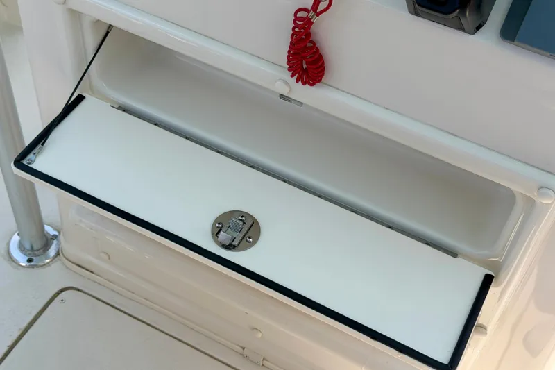 Slide: The Image of 2026 Sea Chaser 22 HFC boat storage compartment with latch and red coiled cord. - 49
