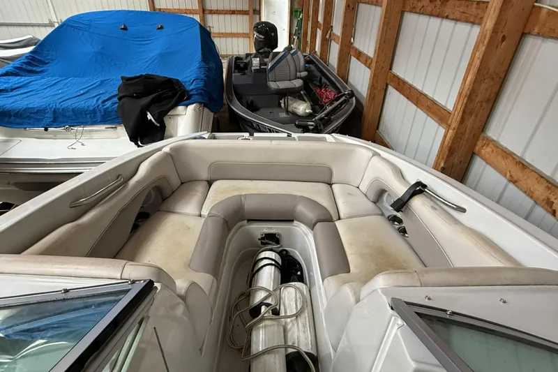 Slide: The Image of 2015 Crownline Eclipse E2 XS boat interior in storage, featuring beige seating and equipment. - 13