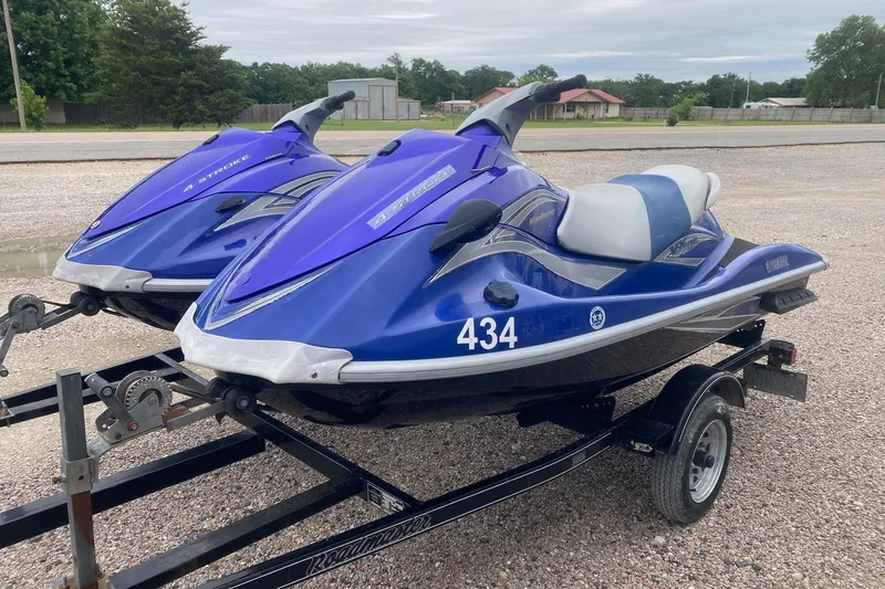 Slide: The Image of 2006 Yamaha WaveRunner VX Cruiser jet skis on a trailer, parked on gravel. - 2