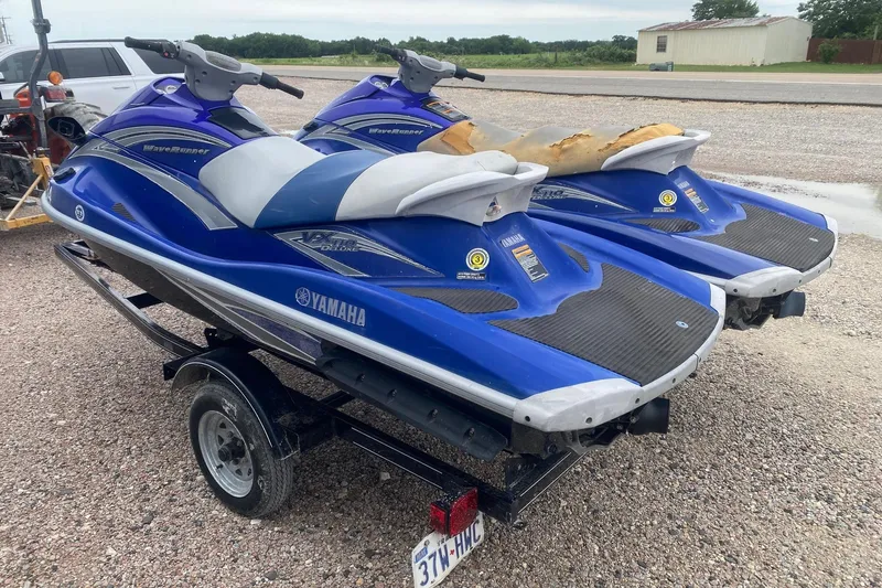 Slide: The Image of Two blue 2006 Yamaha WaveRunner VX Cruisers on a trailer, parked on gravel. - 3