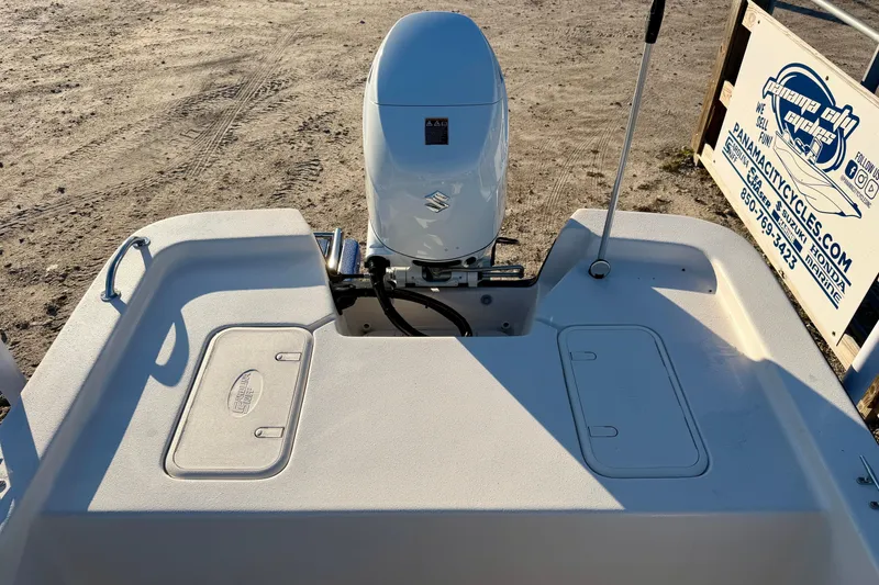 Slide: The Image of 2026 Carolina Skiff E18 JVX CC boat with outboard motor, parked on sandy terrain. - 15