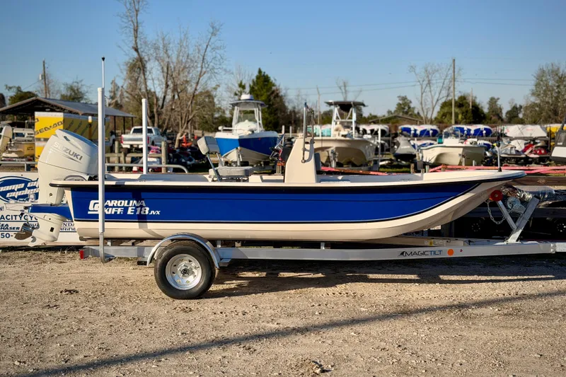 Slide: The Image of 2026 Carolina Skiff E18 JVX CC boat on trailer, parked outdoors. - 2