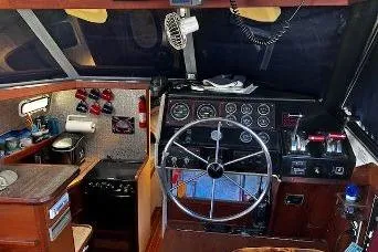 Slide: The Image of 1985 Bayliner 3270 Motoryacht helm with steering wheel, gauges, and kitchen area. - 3