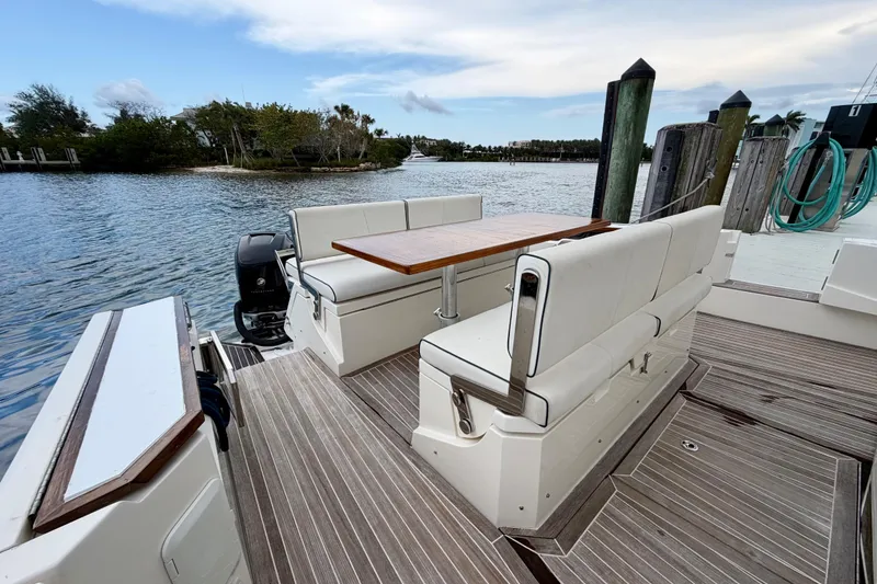 Slide: The Image of 2014 Azimut Verve 40 yacht with outdoor seating and table, docked by a scenic waterway. - 42