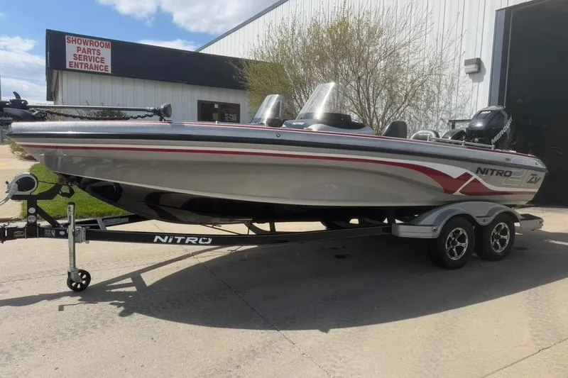The Image of 2015 Nitro ZV21 boat on trailer outside showroom, featuring sleek design and dual consoles. - 0