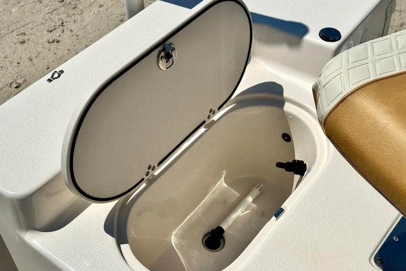 Slide: The Image of Open storage compartment on 2025 Carolina Skiff 178 JLS boat, featuring white interior and cushioned seat. - 6