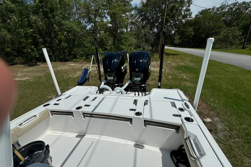 Slide: The Image of 2024 Tidewater 2700 Carolina Bay boat with dual 300 horsepower engines, parked on grass. - 8