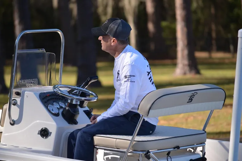 Slide: The Image of Manufacturer Provided Image: Man seated on a 2025 Carolina Skiff 178 JLS boat, wearing a cap and white shirt. - 34