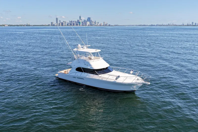 Slide: The Image of 2006 Riviera 47 Open Flybridge yacht on calm waters with city skyline backdrop. - 2