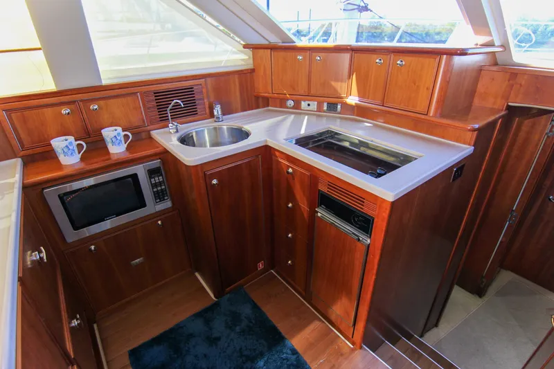 Slide: The Image of Luxurious 2006 Riviera 47 Open Flybridge Series II yacht kitchen with wood cabinetry and modern appliances. - 30