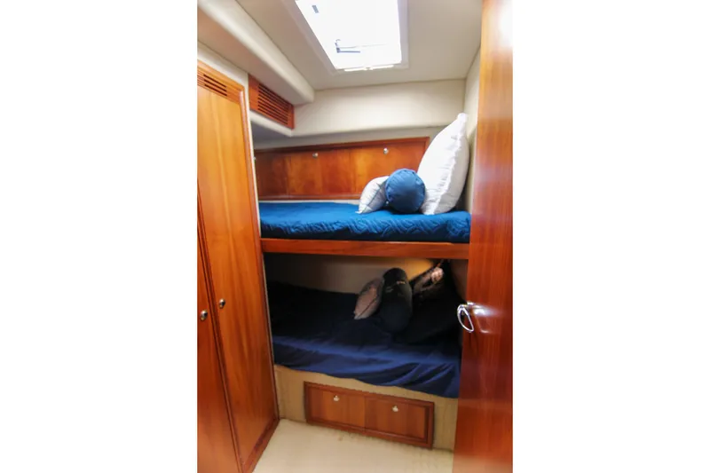Slide: The Image of 2006 Riviera 47 Open Flybridge Series II cabin with wooden bunk beds and blue bedding. - 32