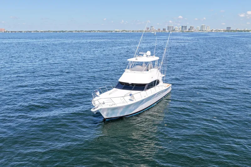 Slide: The Image of 2006 Riviera 47 Open Flybridge yacht on calm blue waters, city skyline in background. - 61