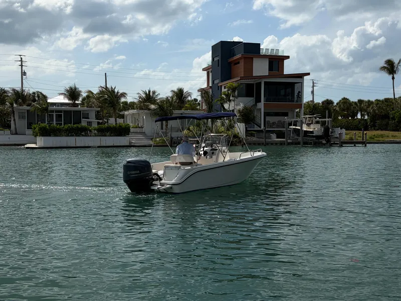 Slide: The Image of 2013 Edgewater 170CC boat on calm water near modern houses. - 7
