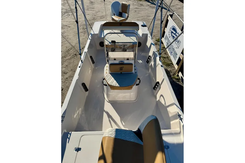 Slide: The Image of 2025 Carolina Skiff 192 JLS boat interior with seating and console, parked outdoors. - 16