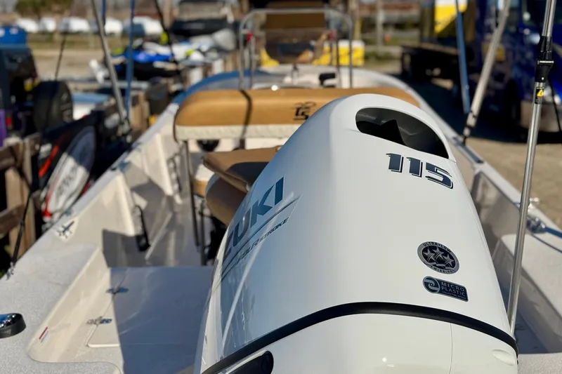 Slide: The Image of 2025 Carolina Skiff 192 JLS boat with Suzuki 115 engine, docked outdoors. - 2