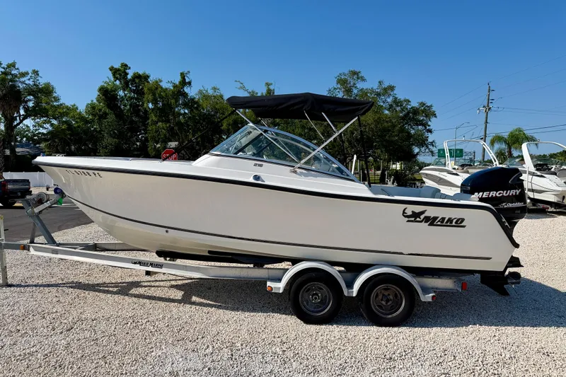 The Image of 2009 Mako 216 Dual Console boat on trailer, parked outdoors under clear blue sky. - 0