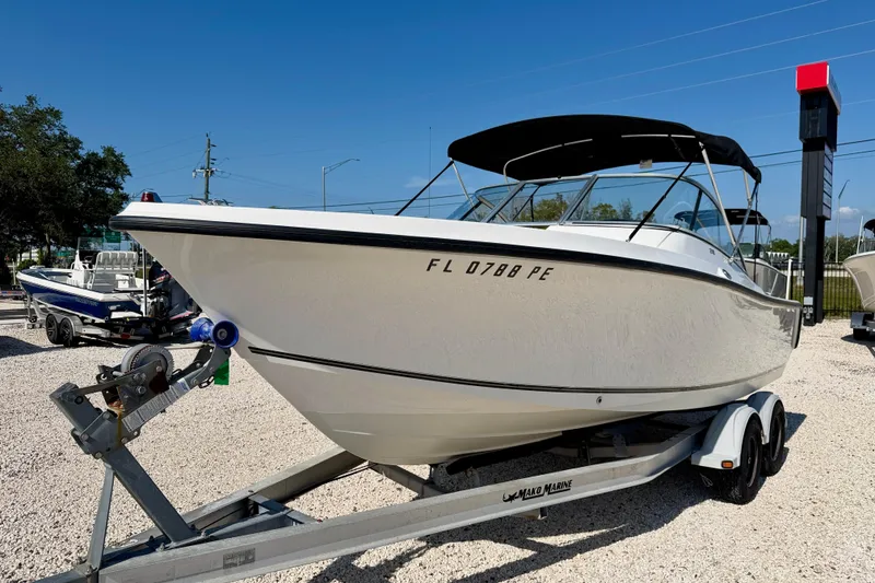 Slide: The Image of 2009 Mako 216 Dual Console boat on trailer, parked outdoors under clear blue sky. - 1