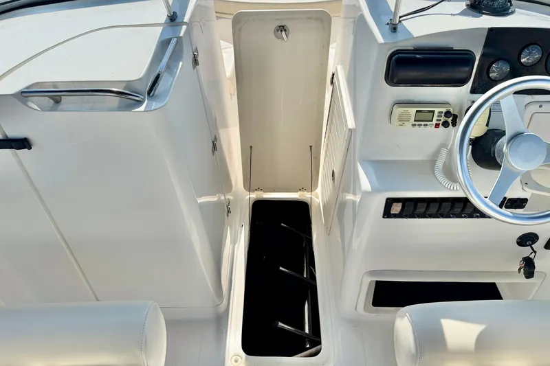 Slide: The Image of 2009 Mako 216 Dual Console boat interior with open storage compartment and steering controls. - 19