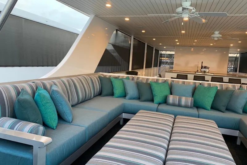 Slide: The Image of Luxurious yacht interior with striped seating, teal cushions, and ceiling fans on Adonia Utopia Trip #8. - 12