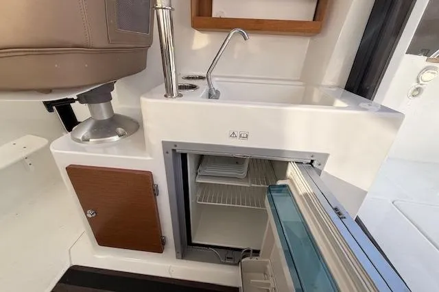 Slide: The Image of Interior of 2018 Jeanneau NC Sport 695 boat with sink and open mini fridge. - 22