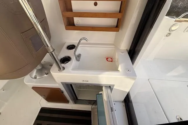 Slide: The Image of Compact kitchenette on 2018 Jeanneau NC Sport 695 boat with sink and mini-fridge. - 23