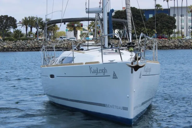Slide: The Image of 2010 Beneteau Oceanis 37 sailboat on calm water near rocky shoreline. - 2