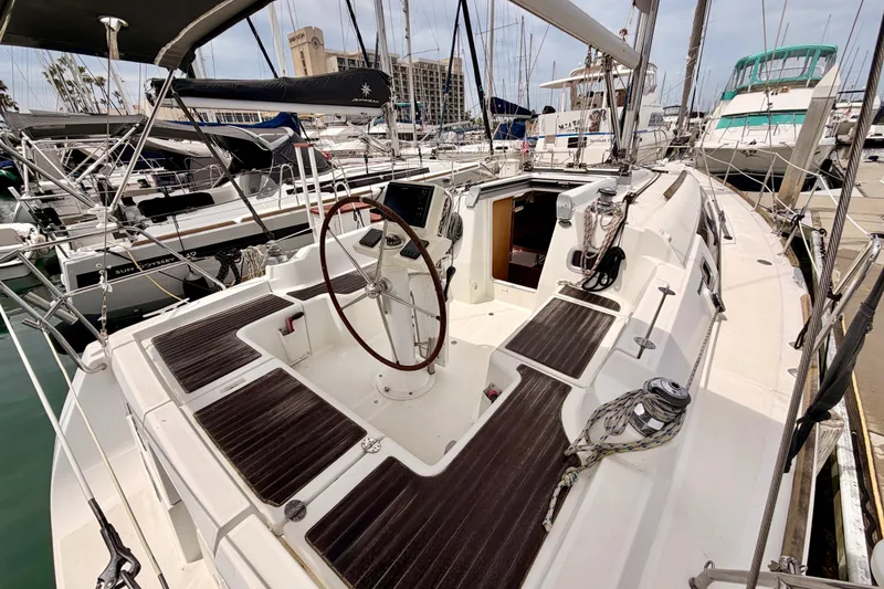 Slide: The Image of 2010 Beneteau Oceanis 34 sailboat cockpit with wooden accents, docked in a marina. - 24