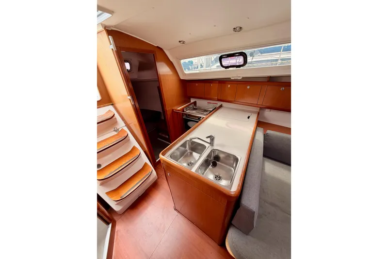 Slide: The Image of Interior of 2010 Beneteau Oceanis 34 sailboat, featuring a compact kitchen and wooden cabinetry. - 41