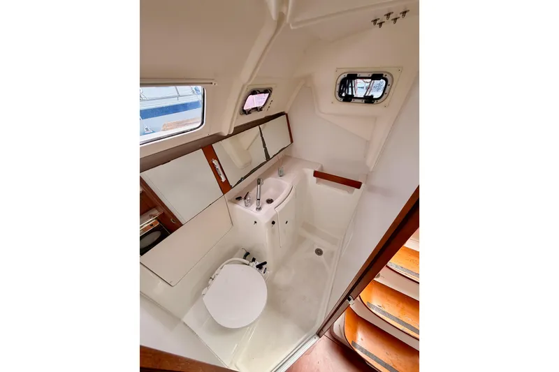 Slide: The Image of Interior view of 2010 Beneteau Oceanis 34 bathroom with sink, toilet, and porthole windows. - 49