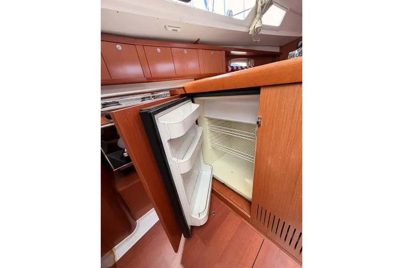 Slide: The Image of Interior view of 2010 Beneteau Oceanis 34 yacht showing open refrigerator in wooden cabinetry. - 67