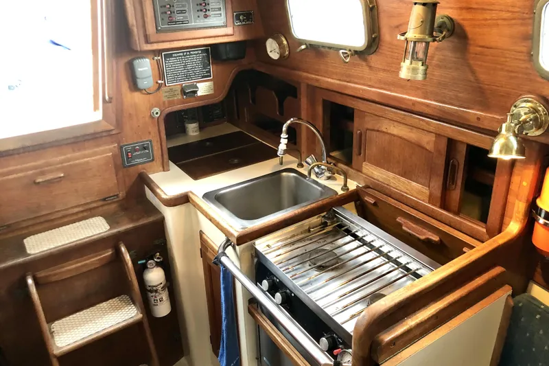 Slide: The Image of 1989 Pacific Seacraft Dana 24 galley with wooden cabinetry, sink, and stove. - 11