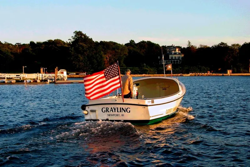 Slide: The Image of Oldport Launch 2026 boat with American flag on water near Newport, RI. - 2