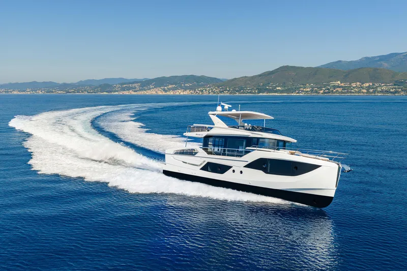 Slide: The Image of 2026 Absolute 62' Navetta yacht cruising on open sea with scenic coastline backdrop. - 4