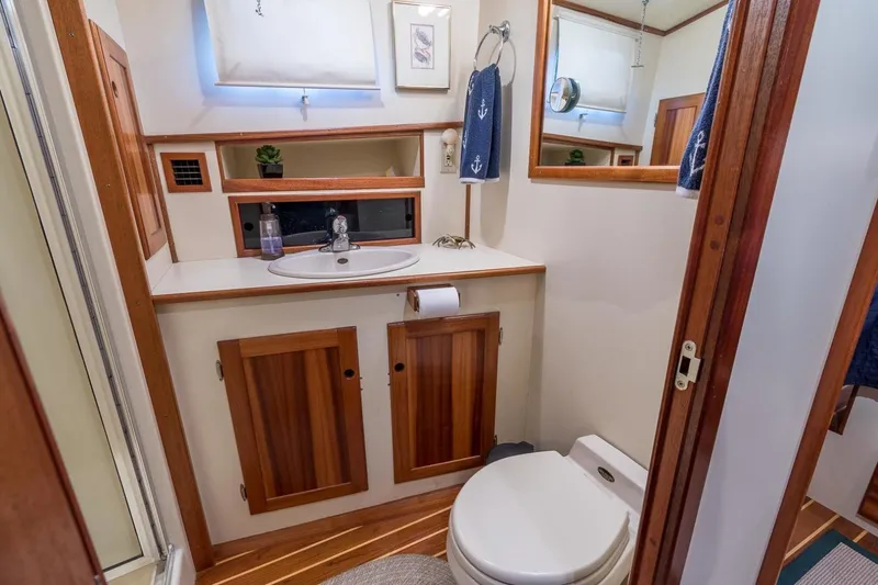 Slide: The Image of Boat bathroom interior with wooden cabinets, sink, and toilet in a 2000 Duffy 42 model. - 12