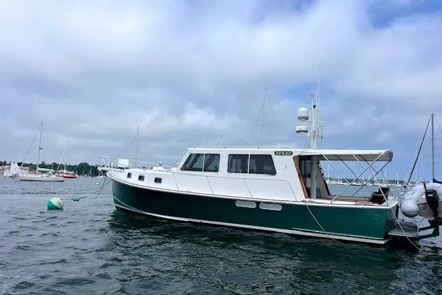 Slide: The Image of 2000 Duffy 42 boat on water, green hull, white cabin, moored with other boats nearby. - 3