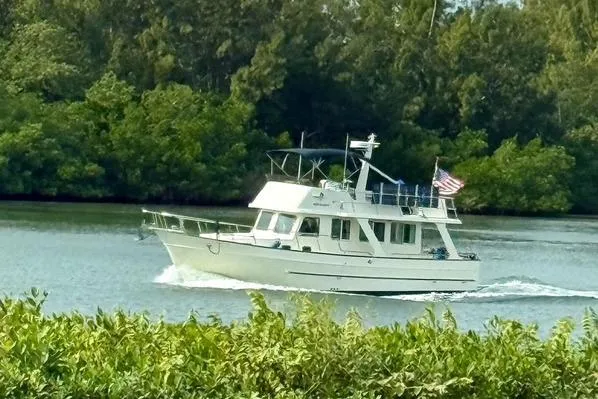 Slide: The Image of 2007 Mariner 40 Orient boat cruising on a scenic river with lush greenery. - 72