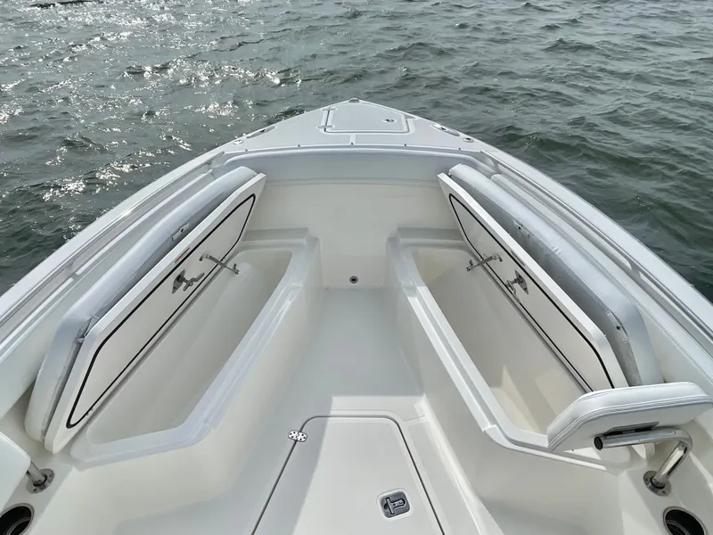 Slide: The Image of 2022 Pursuit S 268 Sport boat with open storage compartments on water. - 32