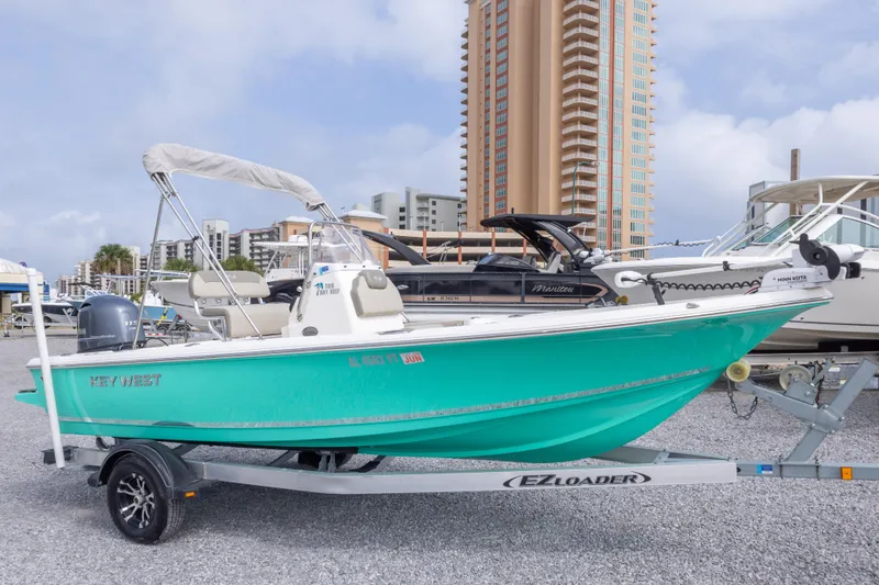 The Image of 2023 Key West 188 Bay Reef boat on trailer, vibrant teal hull, urban backdrop. - 0