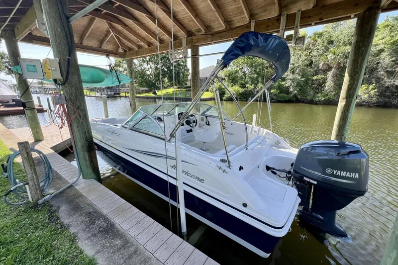 Slide: The Image of 2013 Hurricane SunDeck 187 OB boat docked under a wooden canopy with Yamaha outboard motor. - 14