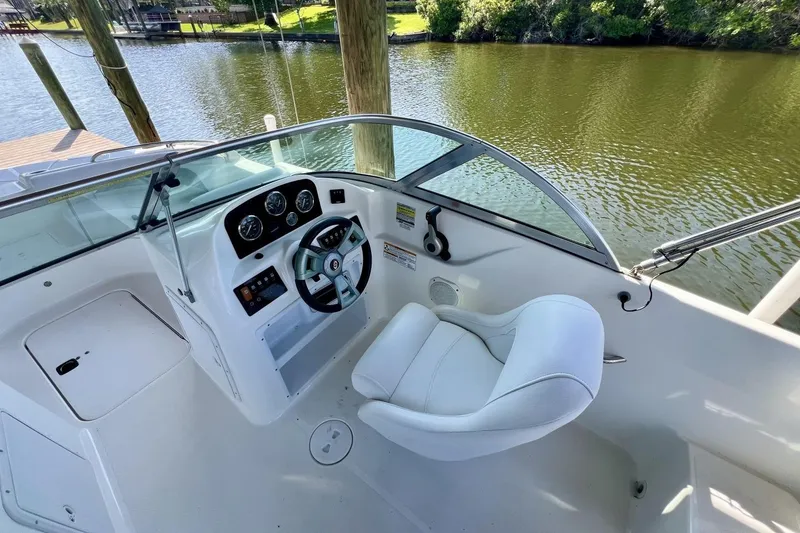 Slide: The Image of 2013 Hurricane SunDeck 187 OB boat cockpit with steering wheel and white captain's chair. - 22