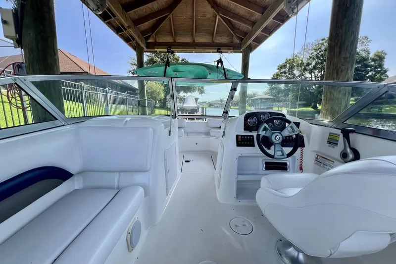 Slide: The Image of 2013 Hurricane SunDeck 187 OB boat interior with white seating and steering wheel under a wooden canopy. - 49