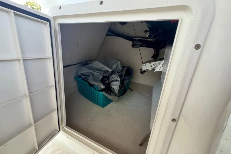 Slide: The Image of Storage compartment inside a 2013 Hurricane SunDeck 187 OB boat, containing a basket and gear. - 54