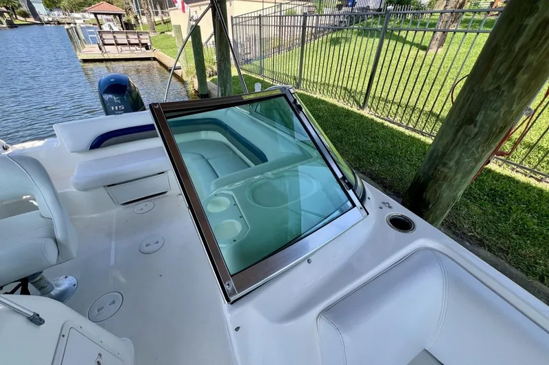 Slide: The Image of 2013 Hurricane SunDeck 187 OB boat interior with seating and windshield by a canal. - 62