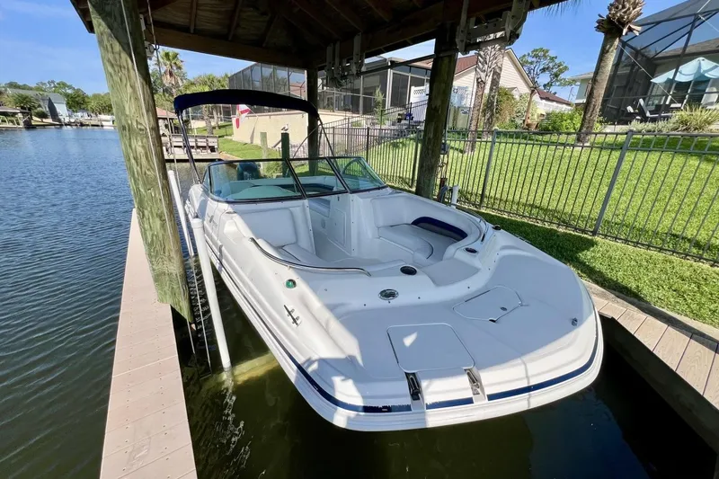 Slide: The Image of 2013 Hurricane SunDeck 187 OB boat docked under a wooden canopy by a lakeside. - 68