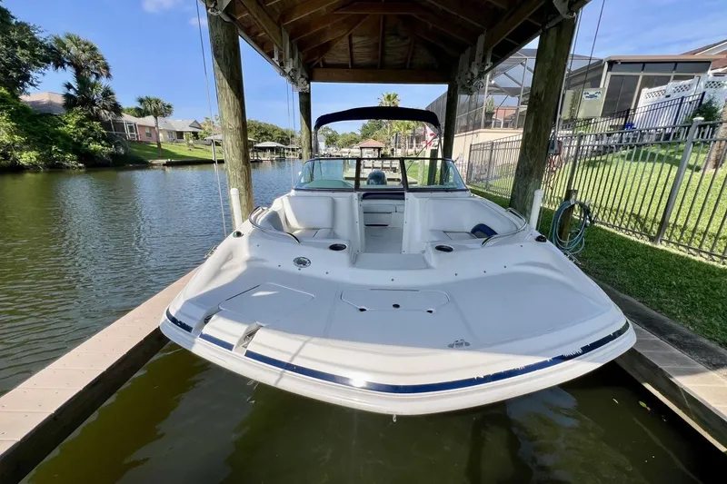 Slide: The Image of 2013 Hurricane SunDeck 187 OB boat docked under a wooden canopy on a calm river. - 69