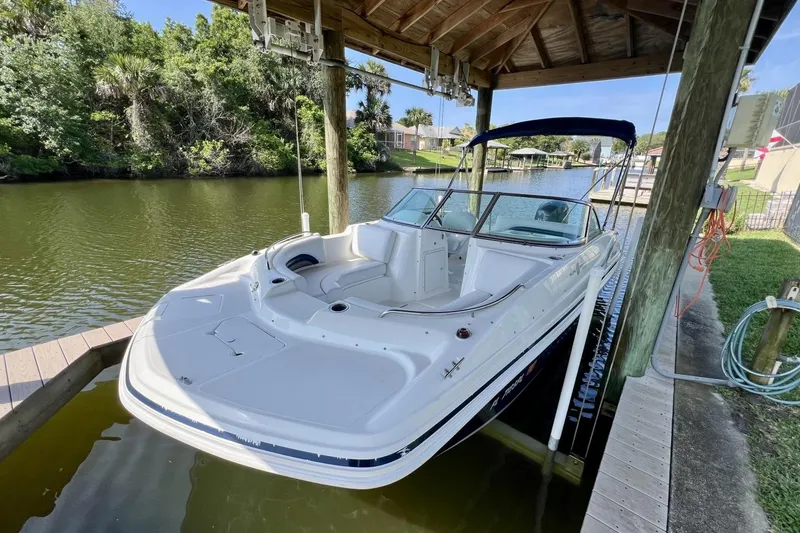 Slide: The Image of 2013 Hurricane SunDeck 187 OB boat docked under a wooden canopy by a scenic river. - 70