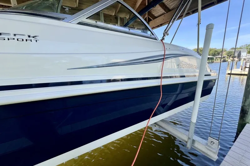 Slide: The Image of 2013 Hurricane SunDeck 187 OB boat docked, featuring sleek design and blue accents. - 75